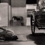 Old man resting on cardboard while collecting cardboard and cans in an alley at night in Clarke Quay, Singapore.