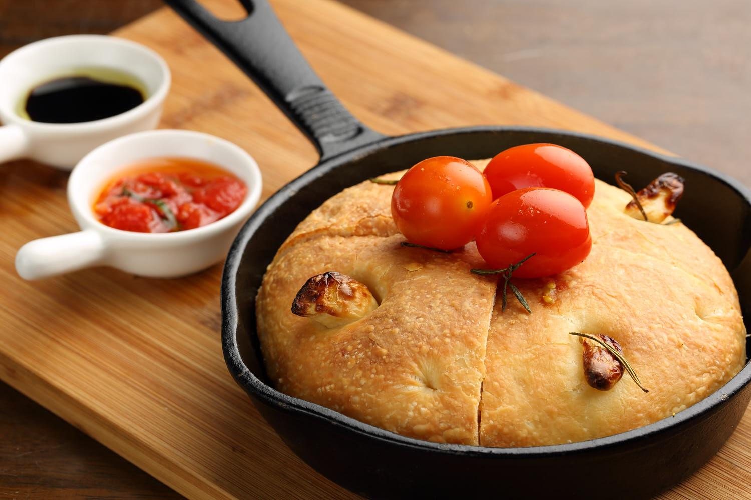 Close-up of crispy pan-baked bread garnished with juicy tomatoes and basil leaves.