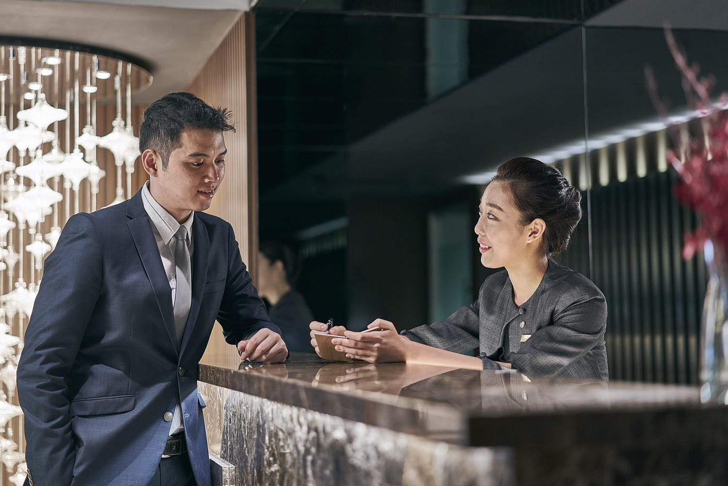 Hotel receptionist warmly checking in guests and providing exceptional service at the front desk.