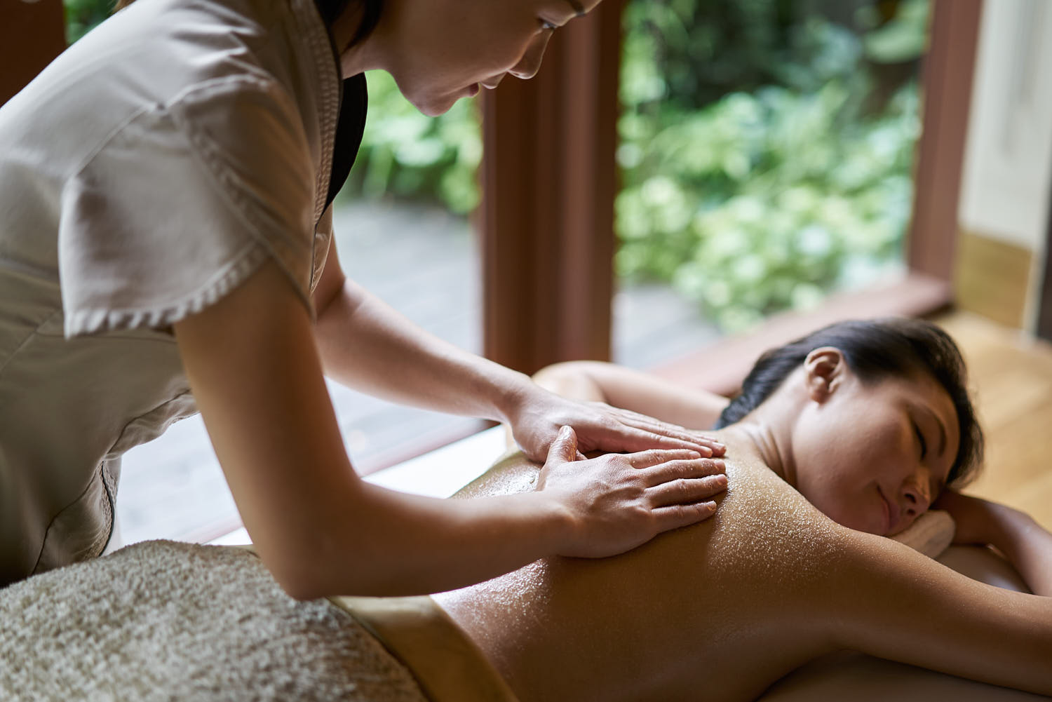 Therapist at a luxury resort spa providing a soothing salt massage therapy session.