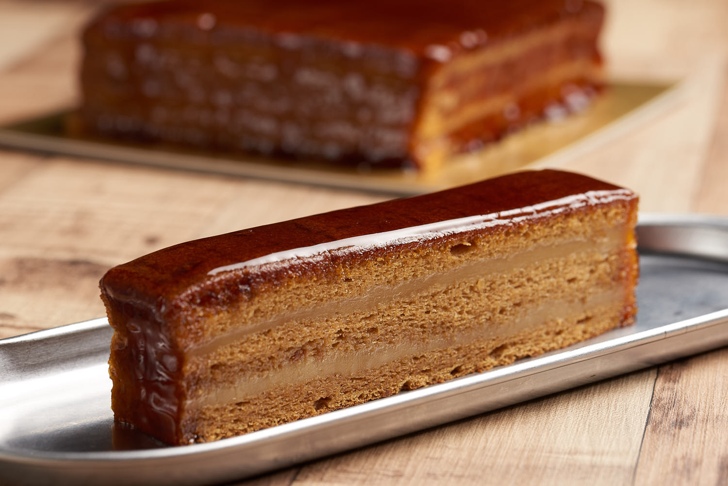 Sinpopo cake slice featuring soft layers and gula melaka glaze in close-up view.