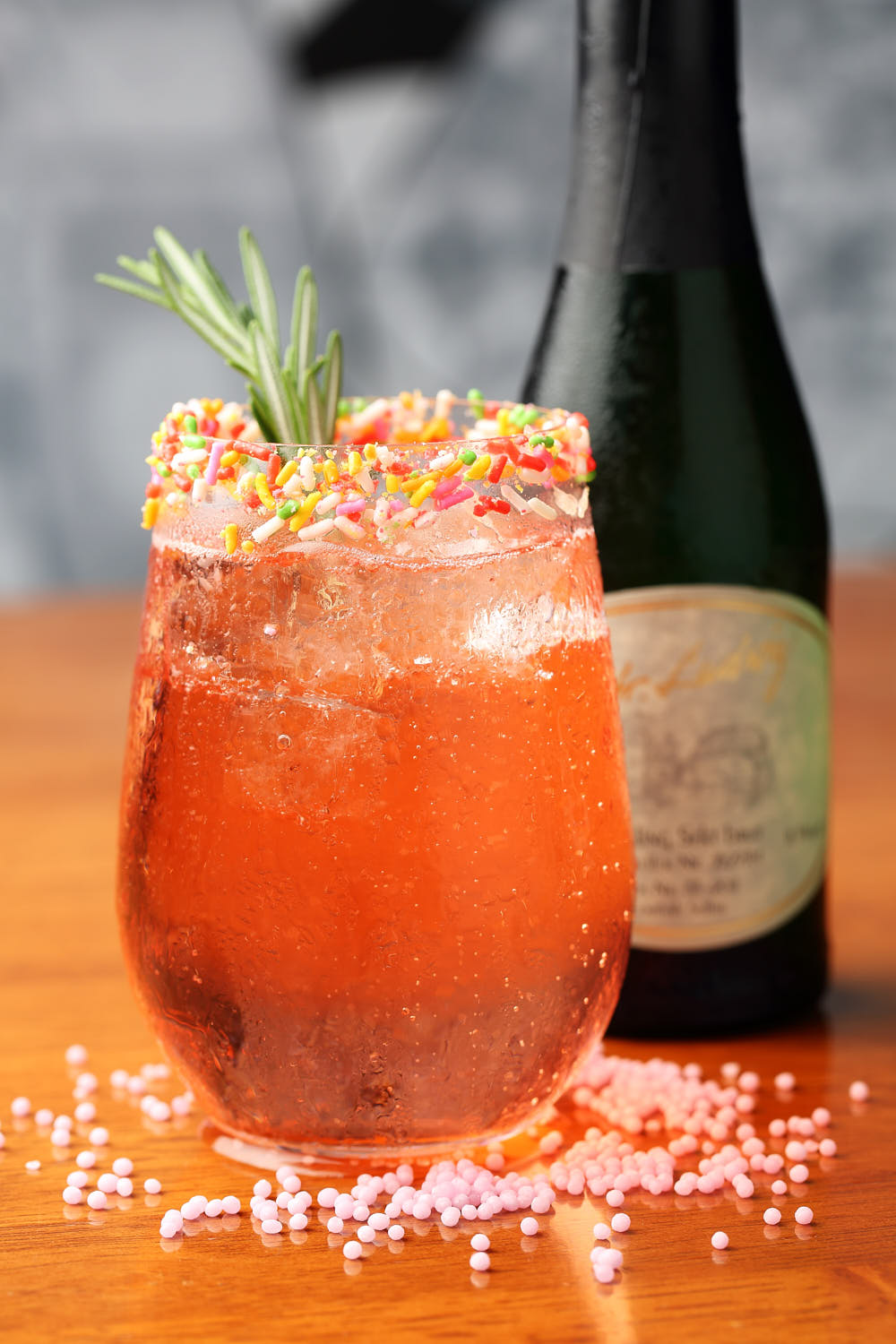 Refreshing red mixed drink decorated with assorted candy for a playful look.