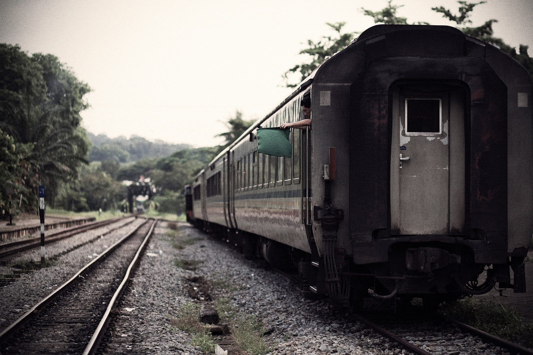 Fine art image of a stationary KTM train at Bukit Timah Railway Station, 1 Blackmore Drive, Singapore, with the train conductor peeking out of the resting train.