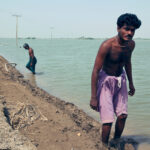 Two men packing soft soil near a levee to delay its collapse in Sujawal, Pakistan, August 2010.