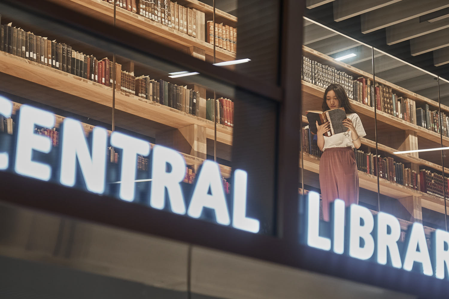 University student immersed in a book while studying in the peaceful library setting.