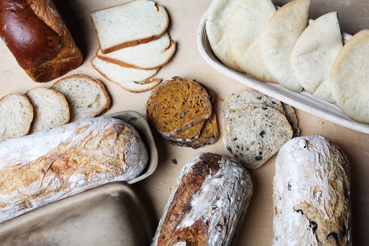 Top-down shot of a variety of artisan breads, including sourdough, baguettes, and whole grain loaves.