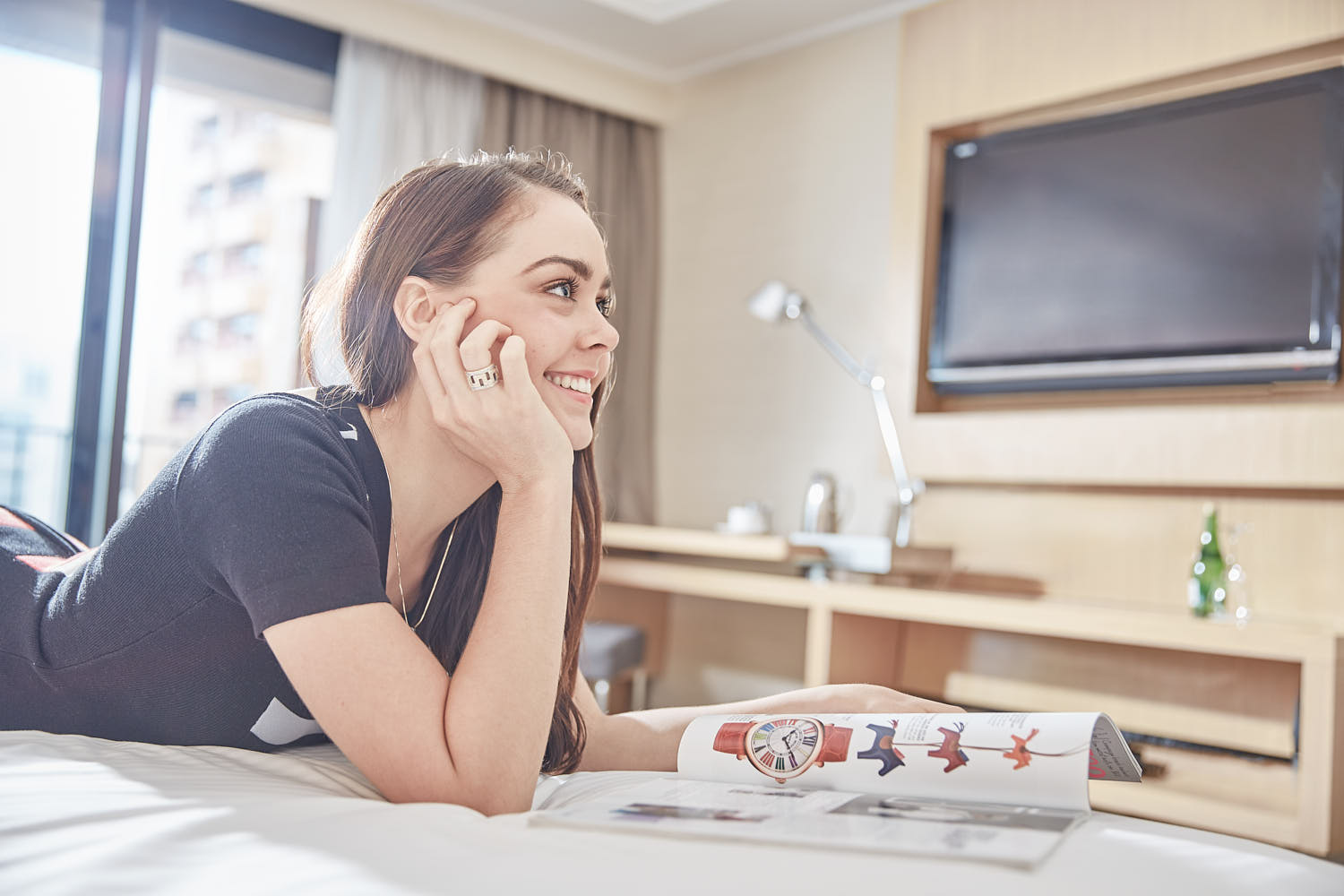 Woman unwinding in a lavish hotel suite, enjoying a peaceful bed retreat.