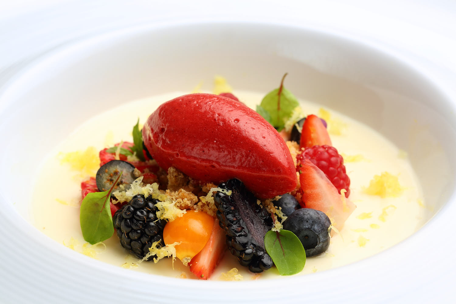Fresh berries soaked in vanilla sauce, topped with a scoop of vibrant sorbet.